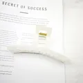 Close-up of a large white glossy hair claw clip on a minimalist book background view - Glossy Jelly White
