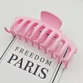 Primer plano de una pinza para el cabello rosa mate grande con diseño de dientes cruzados. - Rosa