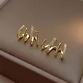 Detail macro view of elegant gold claw earrings pavé-set with brilliant white crystals - Four-prong Zirconia / Gold