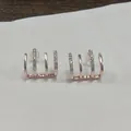 Close-up detail of rose gold claw-shaped earrings with sparkly rhinestone accents - Four-prong Zirconia / Rose Gold