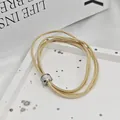Gros plan d'un élastique à cheveux beige haute élasticité avec une perle facettée. - Kaki