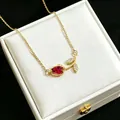 Elegant gold tulip pendant necklace with red gemstone detail on white jewelry box - Red