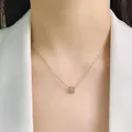 Macro view of an elegant gold-tone titanium steel necklace with a sparkling solitaire gem - Necklace / Gold
