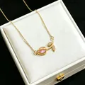 Detailed macro shot of a gold tulip necklace with a pink crystal pendant on a white box - Pink