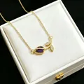 Detailed macro view of a gold tulip necklace with a purple stone and pavé leaves - Purple