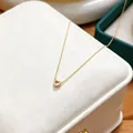 Detailed close-up of an elegant gold heart pendant necklace with shimmering zircon stones - June White