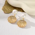 Detailed view of gold shell earrings with elegant white pearls. - Gold Pearl Shell