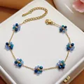 Detailed macro view of a gold stainless steel chain adorned with blue crystal flower charms - Bracelet (5484) / Blue