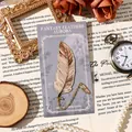 Elegant gold-plated metal feather bookmark with delicate chain on vintage background - Sunny Golden Feather