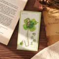 Elegant gilded four-leaf clover metal bookmark presented on a decorative gift card - Emerald Green Clover