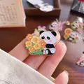 Close-up of a cute panda enamel pin holding orange flowers for backpack decoration - Panda Sunflower (001)