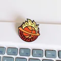 Detailed close-up of a flaming basketball enamel pin on a white keyboard - Flame Basketball Style (C-Model)