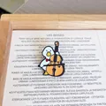 Close-up detail of a cute cartoon duck enamel pin playing a cello on a stylish background - Cello Duck
