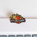 Close-up of a flaming basketball enamel pin with white lettering on a textured surface. - Fastbreak Style (A-Model)