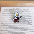 Macro view of a cute cartoon white duck playing a miniature guitar enamel pin - Duck Playing Guitar