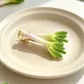 Realistic scallion vegetable hair clip on a minimalist beige ceramic plate detail view - Scallion