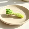 Realistic green lettuce vegetable hair clip on a minimalist cream ceramic plate. - Lettuce Stem