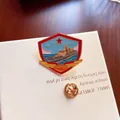 Macro detail of a commemorative metal enamel pin featuring a naval warship and red star. - 056 Corvette