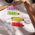 Close-up of four colorful transparent gummy bear hair clips in a wooden tray - Solid Red