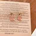 Λεπτομέρεια από ροζ σκουλαρίκια ρακέτα πινγκ πονγκ με πέρλα σε ένα μπεζ φόντο - Ροζ Ρακέτα Πινγκ Πονγκ (Καρφωτά Σκουλαρίκια)