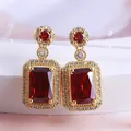 Close-up of elegant red rectangle crystal drop earrings with gold-plated halo setting. - Gold-Ruby Earrings