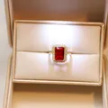 Close-up of elegant emerald-cut red gemstone halo ring in luxury gift box - Gold-Ruby Ring