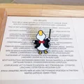 Detail view of a cute cartoon duck conductor enamel pin wearing a tuxedo with red bowtie - Conductor Duck