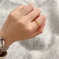 Close-up of a minimalist gold twisted rope ring on a finger with a soft sweater background. - Size 6 / Gold
