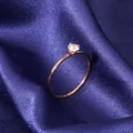 Close-up detail of a minimalist rose gold ring with a single clear sparkling zircon stone. - Size 5 / Rose Gold (331)