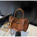 Detail shot of brown suede tote bag featuring buckle strap and beaded charm - With Pendant / Brown