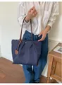 Détail du sac cabas en nylon bleu marine porté par un mannequin chic - Bleu