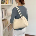 Cremefarbene Leder-Tote-Bag, über der Schulter getragen, in minimalistischer Bibliothek - Basisstil / Weiß