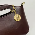 Close-up of brown faux leather handbag with engraved gold RIOA & LUXURY charm detail - No Pendant / Coffee