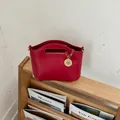 Elegant red women's minimalist handbag with decorative gold charm on wooden shelf - No Pendant / Red