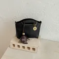 Elegant black faux leather shoulder bag with a stylish woven egg charm accessory - With Pendant / Black