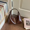 Minimalistische braune glänzende Lackleder-Achseltasche für Damen in Lifestyle-Ansicht - Kaffeebraun