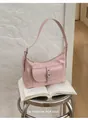 Stylish pink underarm bag for women displayed on an open book in a home setting - Pink