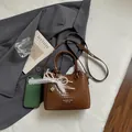 Bolso tipo cubo tejido marrón con colgante de encaje de perlas y correa para el hombro - Café Con Colgante