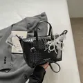 Close-up of a black woven commuter tote bag with elegant lace bow and pearl charm decorations. - Black With Bear Pendant