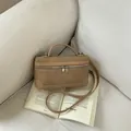 Fashionable tan textured box handbag with crossbody strap displayed on a book prop - Khaki