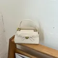 Elegante crèmekleurige handtas met steenpatroon en strikdetail op een houten standaard - Wit