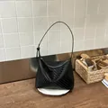 Chic black woven underarm bag featuring a minimalist hobo style with adjustable shoulder strap - Black