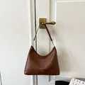 Elegante borsa hobo intrecciata marrone da donna appesa a una maniglia della porta - Taglia L / Marrone