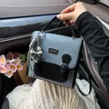 Elegante bolso de tela vaquera azul con solapa negra y un moderno amuleto de lazo metálico - Con Colgante / Negro