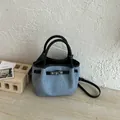 Fashionable denim blue bucket bag featuring black leather handles and a silver turn-lock - No Pendant / Black
