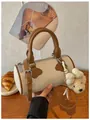 Beige woven barrel handbag for women featuring brown leather handles and a cute teddy bear charm - With Charm / White