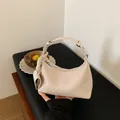 Elegant beige woven dumpling handbag for women featuring a stylish top handle design - White