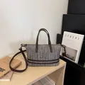 Stylish woven crossbody bag with brown leather handles and decorative chain detail. - Coffee