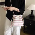Chic pink striped crossbody bucket bag with drawstring and marble accent - Pink
