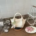 Elegante cremefarbene Eimertasche mit Knotenhenkeln und Perlenanhänger in Tulpenform - Mit Anhänger-Stil / Weiß